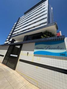 een groot hoog gebouw met een bord erop bij Conforto na Ponta Verde in Maceió