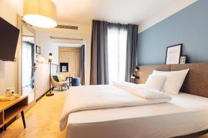 harry's home Berlin-Moabit hotel & apartments في برلين: غرفة نوم بها سرير أبيض كبير ومكتب