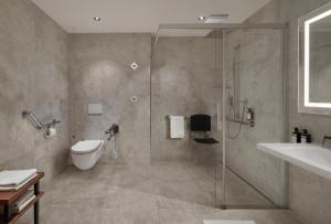 a bathroom with a shower and a toilet and a sink at Hotel Schwarzer Adler Innsbruck in Innsbruck