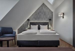 a bedroom with a bed and a blue chair at Hotel Schwarzer Adler Innsbruck in Innsbruck