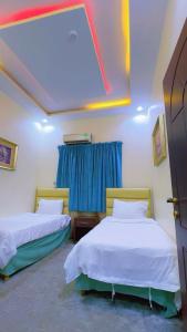 two beds in a room with blue curtains at منتحع سيتي لاند 3 in Taif +19 photos