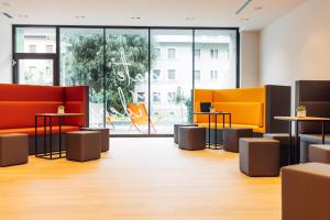 eine Lobby mit orangefarbenen und gelben Stühlen und Tischen in der Unterkunft harry's home Bischofshofen hotel & apartments in Bischofshofen