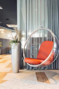 ein roter Stuhl, der in einem Zimmer an einer Kette hängt in der Unterkunft harry's home Telfs hotel & apartments in Telfs