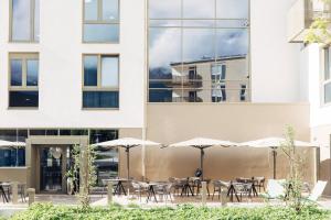 eine Terrasse mit Tischen und Sonnenschirmen vor einem Gebäude in der Unterkunft harry's home Telfs hotel & apartments in Telfs