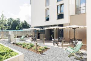 eine Terrasse mit Tischen und Sonnenschirmen vor einem Gebäude in der Unterkunft harry's home Telfs hotel & apartments in Telfs + 88 Fotos