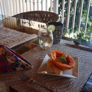 a plate of fruit on a table with a glass at Hale Hualalai in Kailua-Kona +24 photos