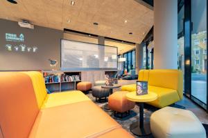 ザルツブルクにあるharry's home Salzburgの黄色い椅子とスクリーンが備わる待合室