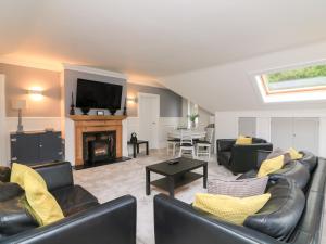 a living room with leather furniture and a fireplace at 1 The Old Coach House in Dartmouth