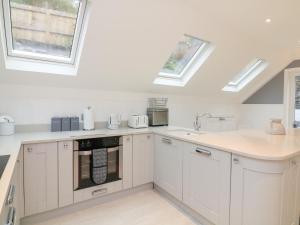 a kitchen with white cabinets and skylights at 1 The Old Coach House in Dartmouth