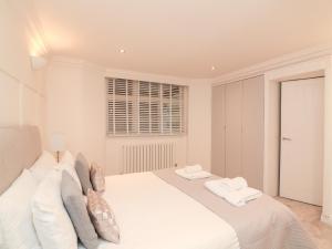 a white bedroom with a large white bed with pillows at 1 The Old Coach House in Dartmouth