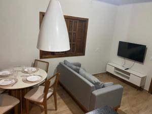 a living room with a couch and a table and a tv at Sítio Anna in São Thomé das Letras