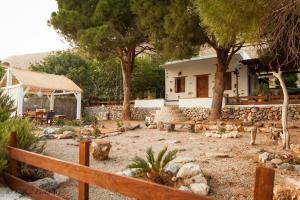 een tuin voor een huis met bomen en bankjes bij The Corsair Cottage in Kalymnos