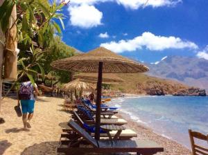 a group of beach chairs and umbrellas on a beach at The Corsair Cottage in Kalymnos +6 photos