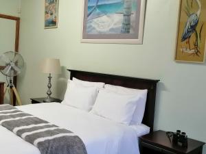 83 Ocean View في بورت شيبستون: غرفة نوم بسرير مع شراشف بيضاء ومروحة