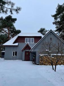 a barn with a red door in the snow at Piejūras māja skandināvu stilā! Seaside scandi house! in Lapmežciems