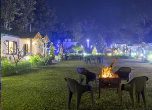 ein Feuer im Garten bei Nacht mit Lichtern in der Unterkunft Corbett Mid Forest House By Havensia Stays in Rāmnagar