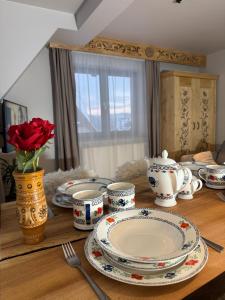 GÓRALSKIE NOWE APARTAMENTY BIAŁKA - Skibus, Sauny, Bania, Sale zabaw - w cenie في بيالكا تاترزانسكا: طاولة مع صحون واكواب و مزهرية مع وردة