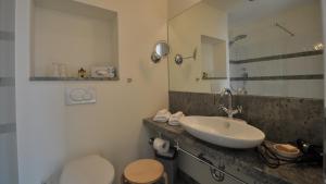 a bathroom with a sink and a toilet and a mirror at Villa Andante Apartmenthotel in Kassel