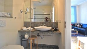 a bathroom with a sink and a person in a mirror at Villa Andante Apartmenthotel in Kassel