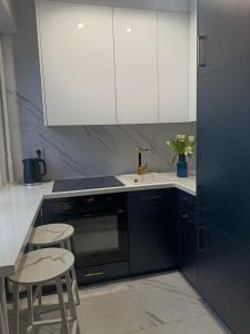 a kitchen with white cabinets and a sink and chairs at Blue Royal Luxury Apartment z HBO Max in Tarnów