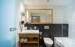 a bathroom with a sink and a toilet and a tub at Hotel Taescherhof in Täsch