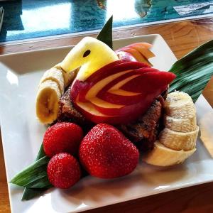 a sandwich with a chicken on a plate with strawberries at Hale Hualalai in Kailua-Kona
