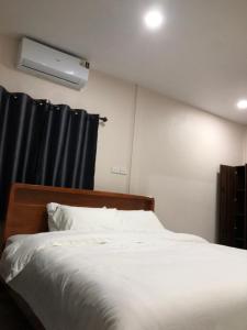 een slaapkamer met een wit bed en zwarte gordijnen bij The Sun homestay in Ko Kood