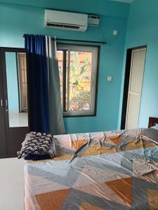 a bed in a room with a blue wall and a window at Casa De D'souza in Mandrem