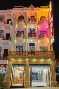 a large white building with a neon sign on it at Phương Anh Hotel in Mèo Vạc