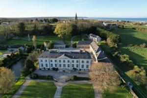 an aerial view of a large white house with a yard at Le Château de Quinéville in Quinéville