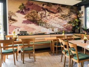 a restaurant with wooden tables and chairs and a mural at Lemp's Genussgarten in Langenargen +19 photos