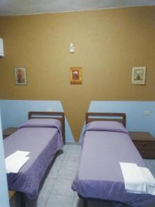 two beds in a room with purple sheets at La Locanda del Re in Crevalcore