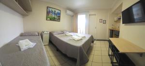 a hotel room with two beds and a television at Flat 8A confortável e completo próximo ao Hot Park e Pousada do Rio Quente in Rio Quente