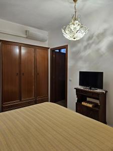 a bedroom with a bed and a television and a chandelier at La Corte dei Nonni in Vanzaghello