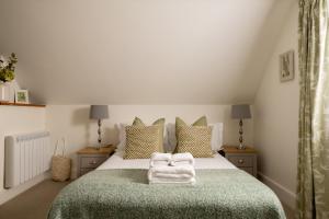 a bedroom with a bed with a green blanket and pillows at Magnolia Cottage-Exclusive Cotswold Package in Moreton in Marsh