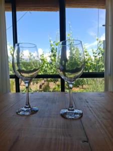 two wine glasses sitting on top of a wooden table at El Atelier - Valle de Uco in La Consulta