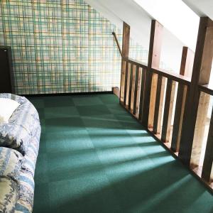 Zimmer mit grünem Teppichboden und einem Bett in der Unterkunft Petit Hotel Blanc Fleur in Nakafurano