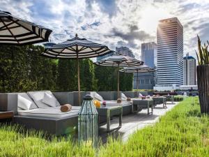 a patio with umbrellas and couches and tables at Mövenpick Hotel Sukhumvit 15 Bangkok in Bangkok