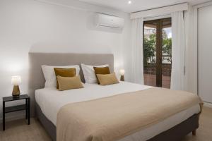 a bedroom with a large white bed with yellow pillows at Baía II by An Island Apart in Funchal