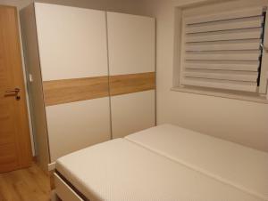 una piccola camera da letto con un letto e una finestra di Apartmaji Divji vrt a Lendava