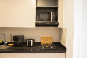 a kitchen with a stove and a microwave at Moderno apartamendo con Rooftop y Jacuzi in Dosquebradas