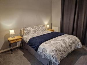 a bedroom with a bed with two lamps on tables at Home Sweet Home, Calverley Court Apartment Home in West Midlands, England in Parkside