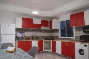 una cocina con armarios rojos y blancos y una mesa en Elegant Villa with Private Pool in South Hammamet 2P, en Hammamet Sud
