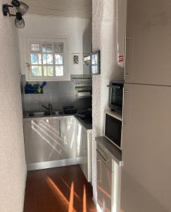 a small kitchen with a sink and a microwave at Idyllique ! Terrasse vue jardin et montagne, parking, local à vélos, à 2 pas de la plage et piscine de mai à septembre ! in Argelès-sur-Mer