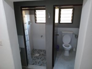 a bathroom with a toilet and two windows at TN apartments voism in Diani Beach +14 photos