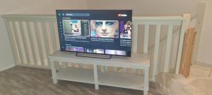 Une télévision à écran plat est installée au-dessus d'une table blanche. dans l'établissement Maison dans résidence CopaCabana, à Saint Pierre La Mer