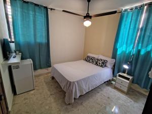 a small bedroom with a bed and blue curtains at Private and comfortable double room in Santo Domingo