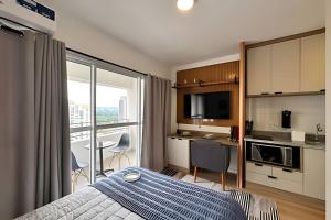 a bedroom with a bed and a kitchen with a balcony at 1412 - Studio completo com varanda e vaga in São Paulo