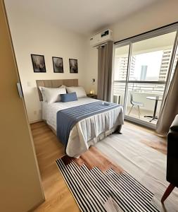a bedroom with a bed and a large window at 1412 - Studio completo com varanda e vaga in São Paulo +23 photos