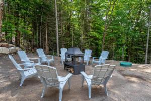a group of chairs and a grill in the woods at Le Birdie spa et sauna in Saint-Faustin